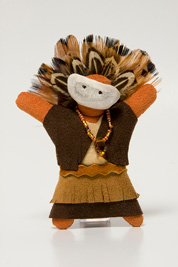 a small doll-like fetish with a headdress of feathers, beaded necklace, mask and dress made of leather.