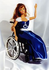 A plastic doll in a blue and white gown with a bodice embellished with the Wheelchair Symbol of Access waves from her wheelchair.