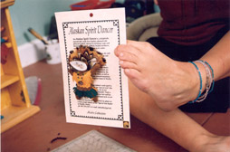 Sabine Becker uses her left foot to hold up a Spirit Dancer fetish attached to a card explaining its legend.